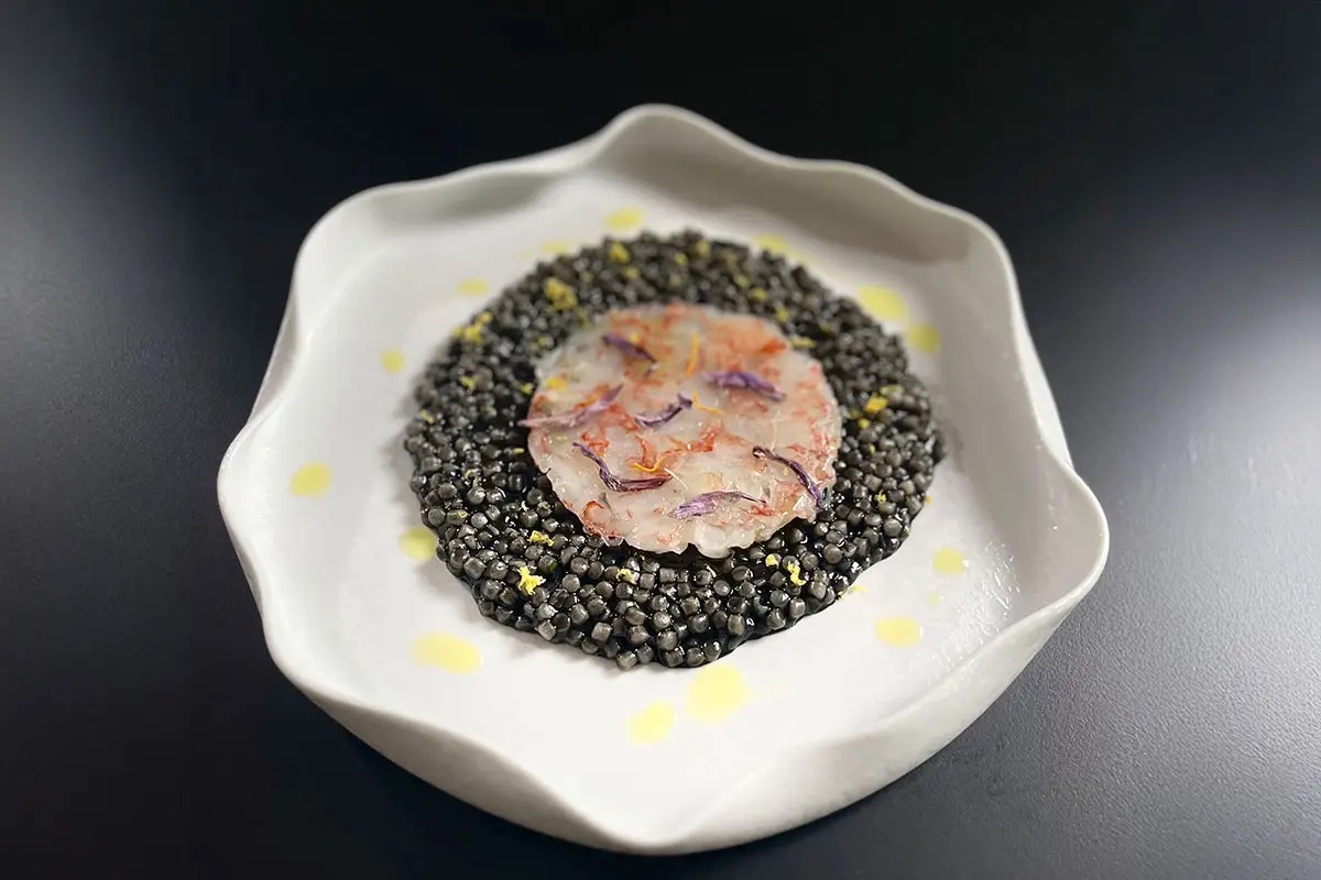  Fregola sarda al nero di seppia servita con carpaccio di gambero